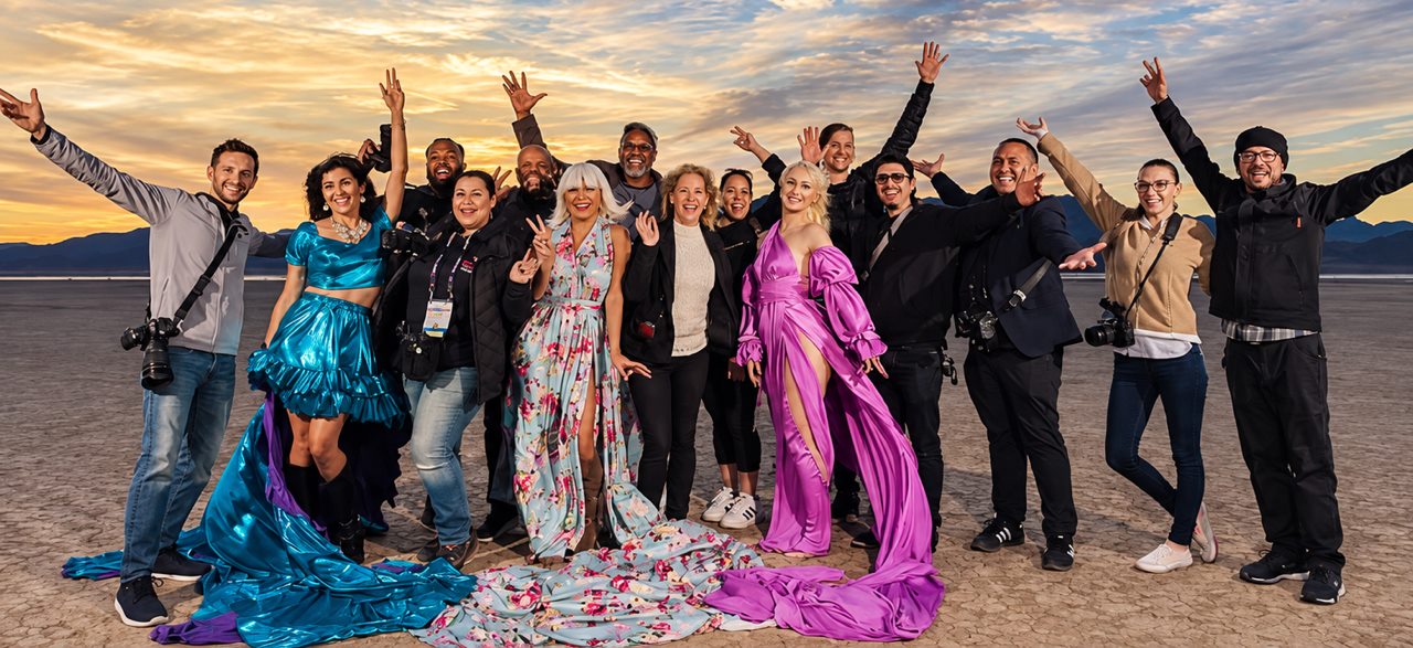 Um grupo de fotógrafos e duas modelos em vestidos voadores em um workshop no deserto ao pôr do sol